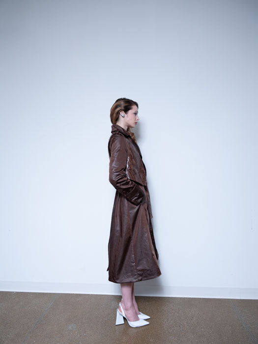 Side of woman wearing a Long Chocolate Bristol Trench coat made of satin with a removable vest in textured leather