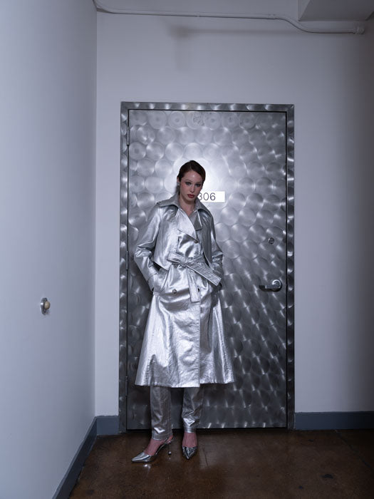 Woman posing while wearing a long water-resistant trench coat in silver coated cotton twill with a back shield for added detail