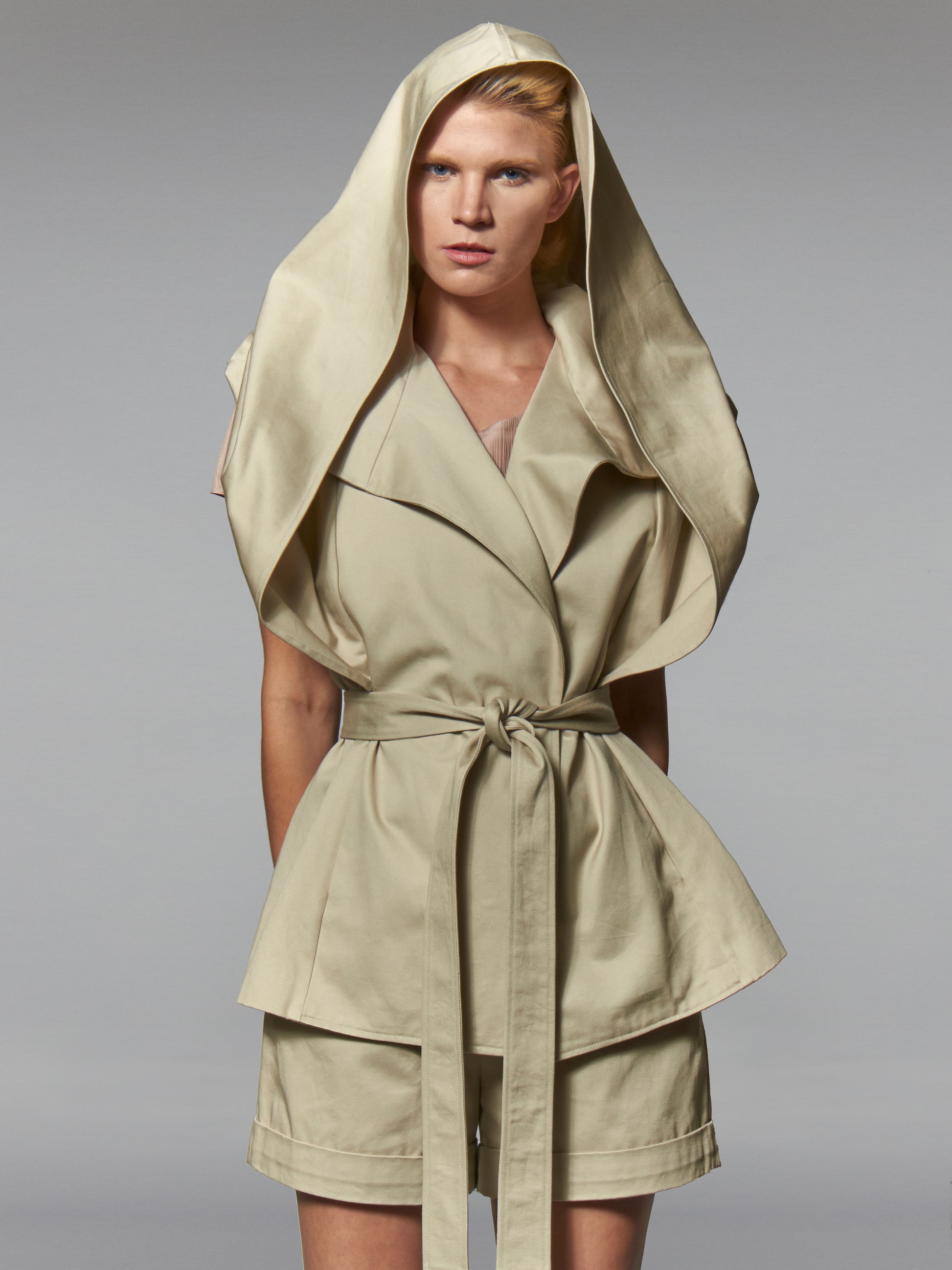 Woman in a beige cotton wrap jacket with transformed hood and self tie belt