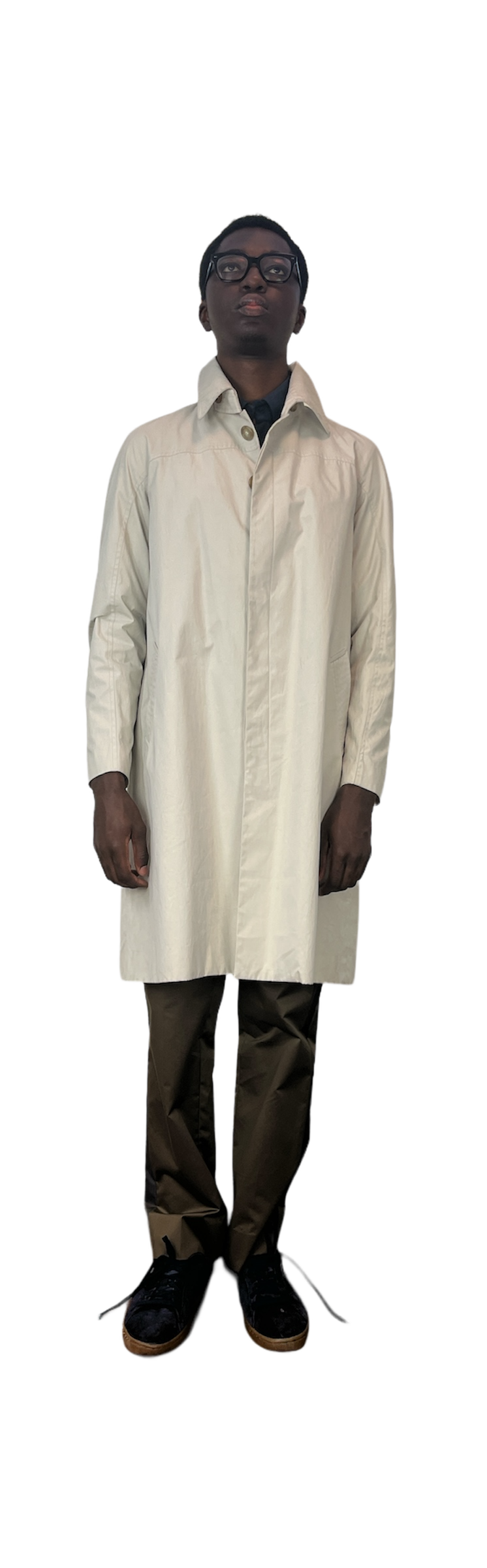 Man wearing off white coat over green pants