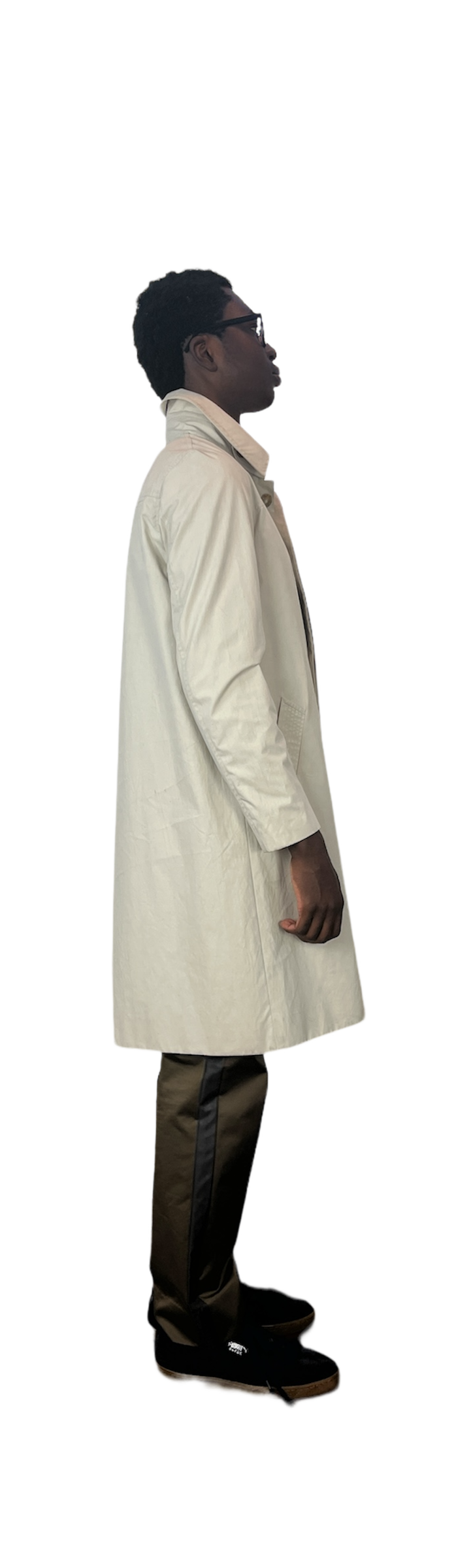 Side of man wearing off white rain coat over green pants