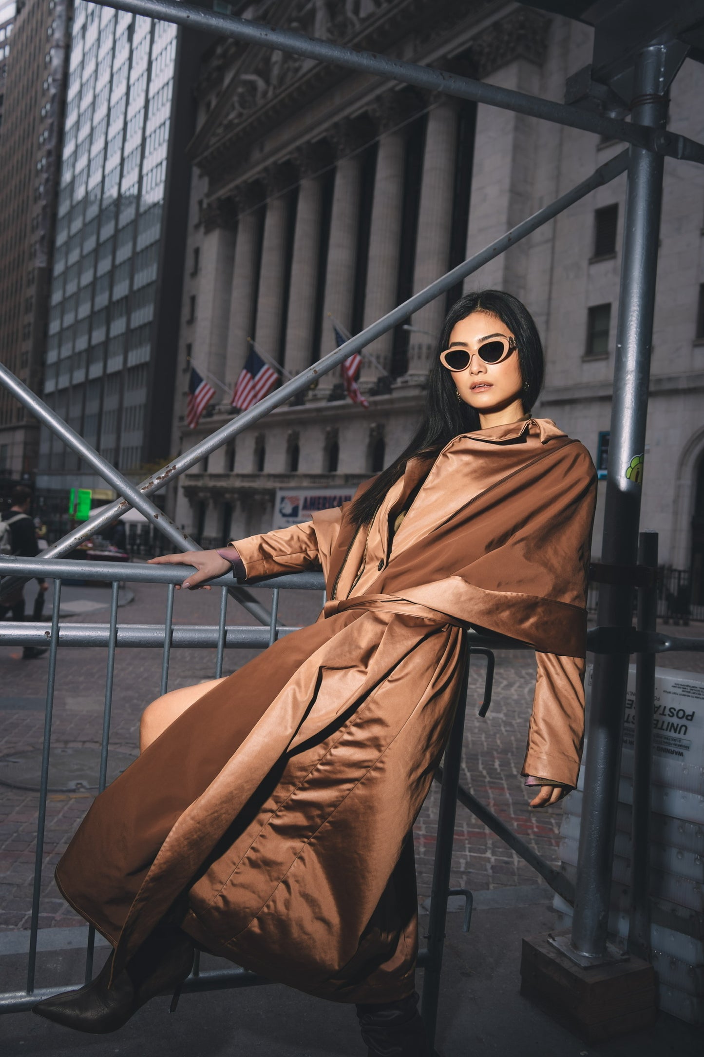 Woman posing with sunglasses and copper stretch satin coat with transformable zippers and self tie belt and high heels