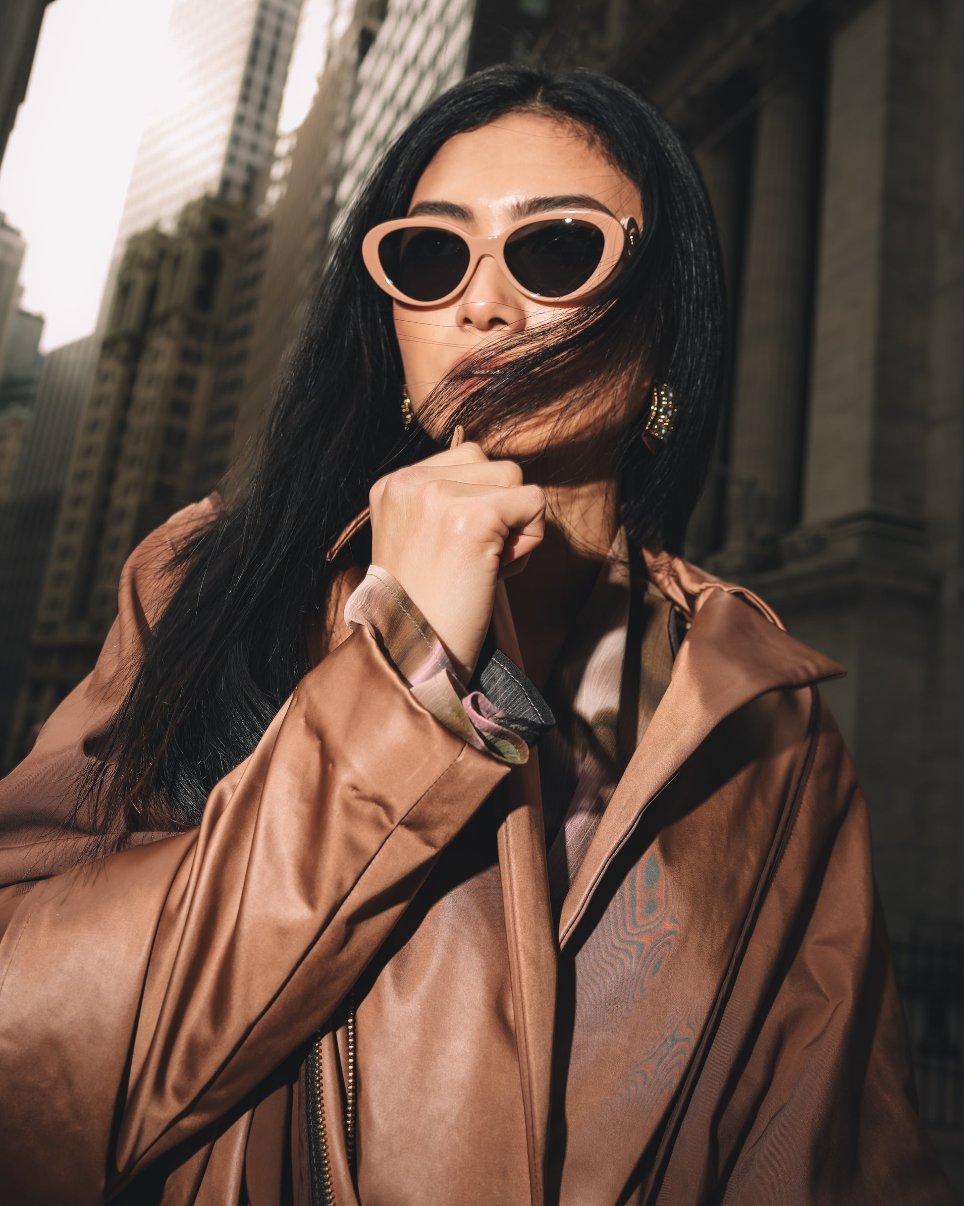 Close up of Woman posing with sunglasses and copper stretch satin coat with transformable zippers and self tie belt