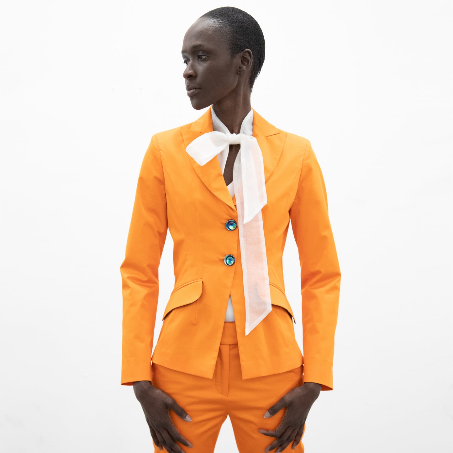 Woman wearing an orange slim fit blazer with a two button closure