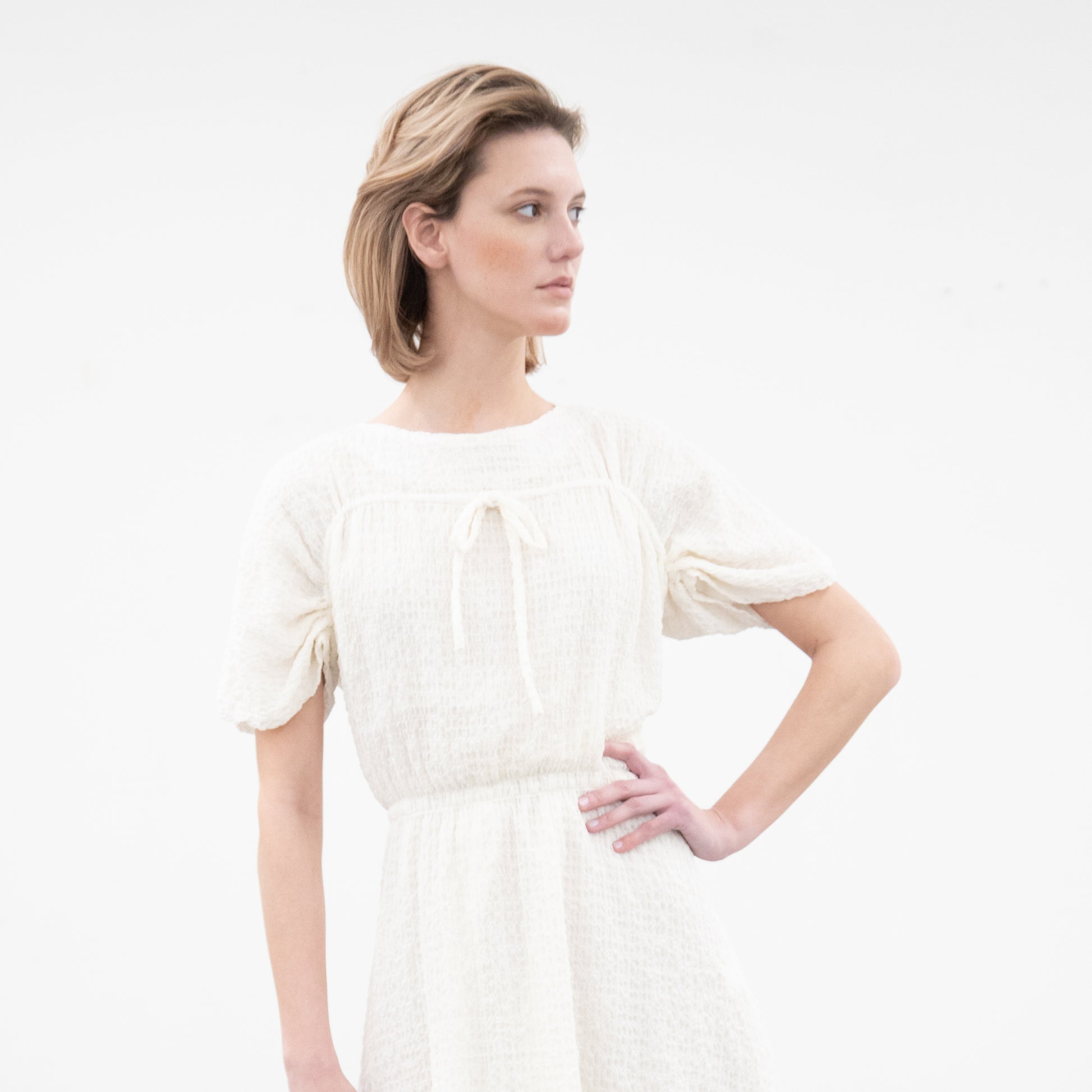 Woman in white midi dress with drawstring detail, adjustable sleeves, and gathered waist