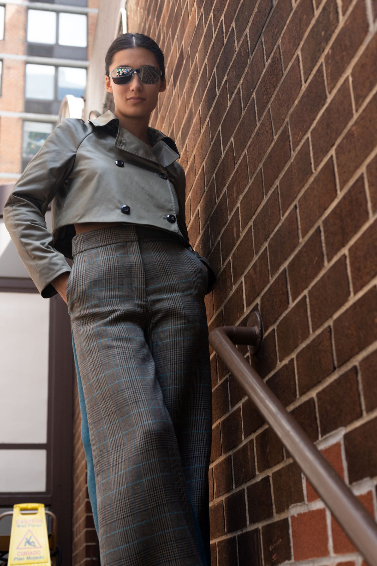 Woman wearing wool blend two tone high waisted flared pants, with double breasted jacket and sunglasses outside