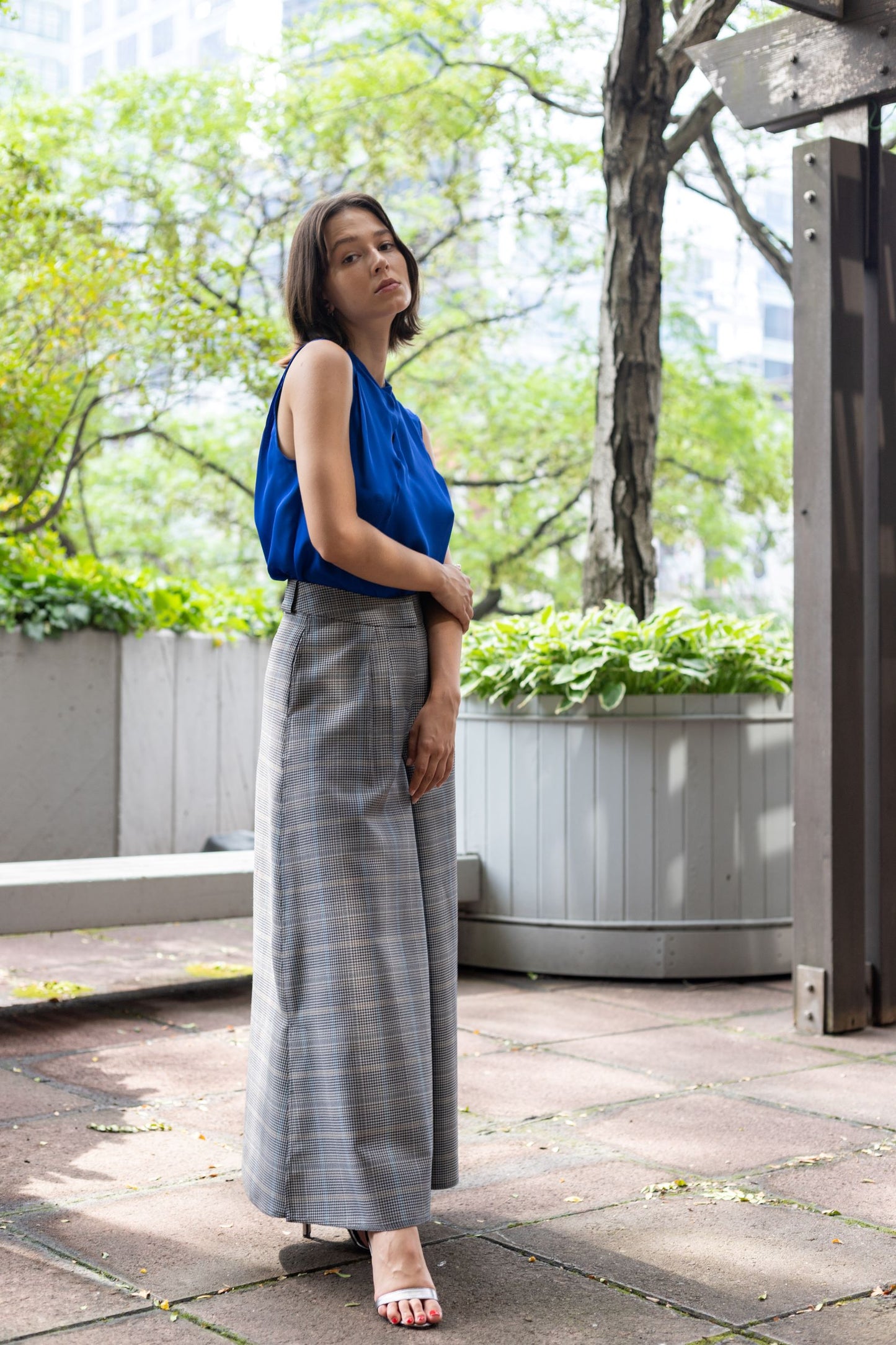 Woman wearing a gray plaid flared pants paired with a cobalt blue kimono top