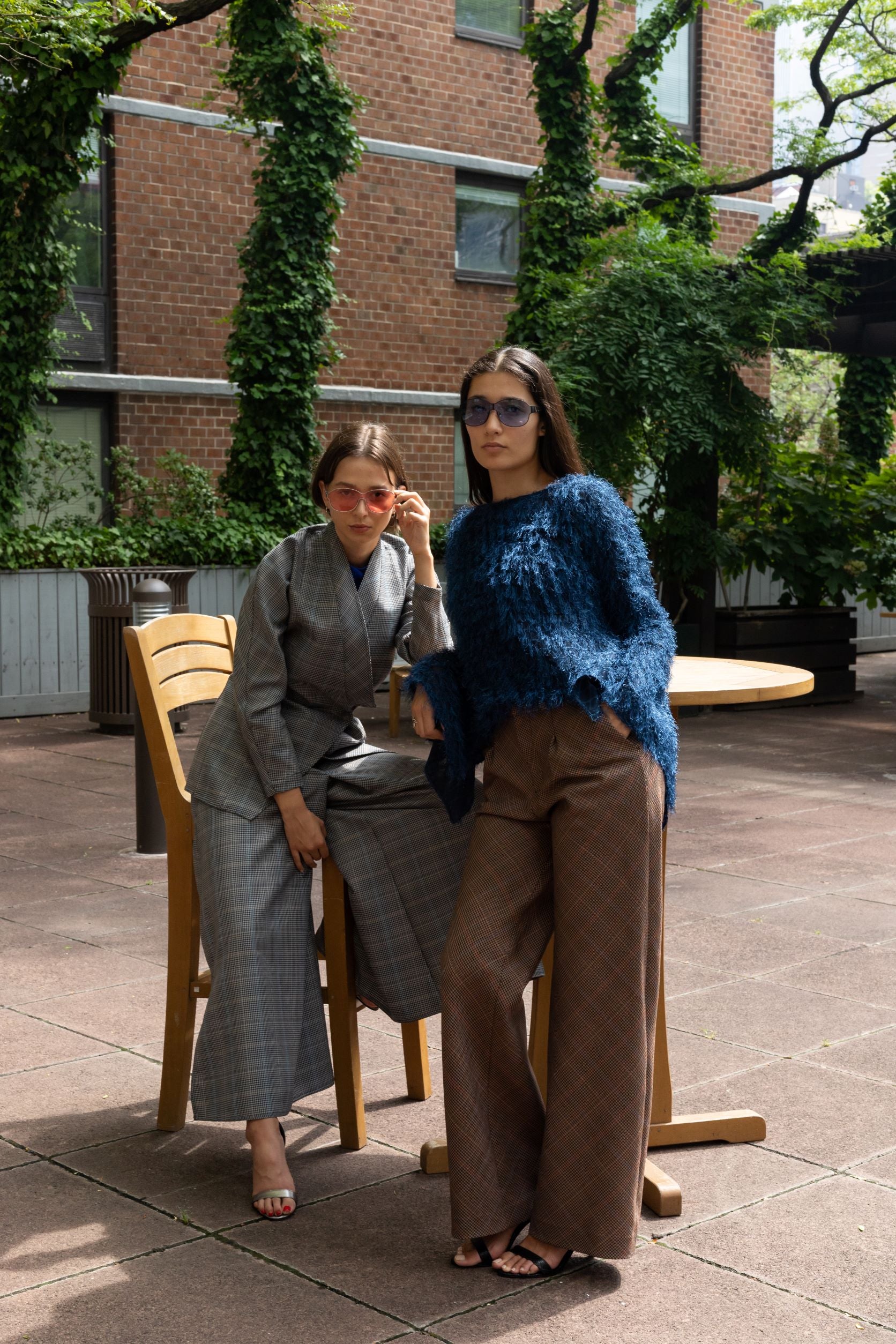 Two women, one in a fluffy blue sweater and brown plaid bias cut pant with opening pleat