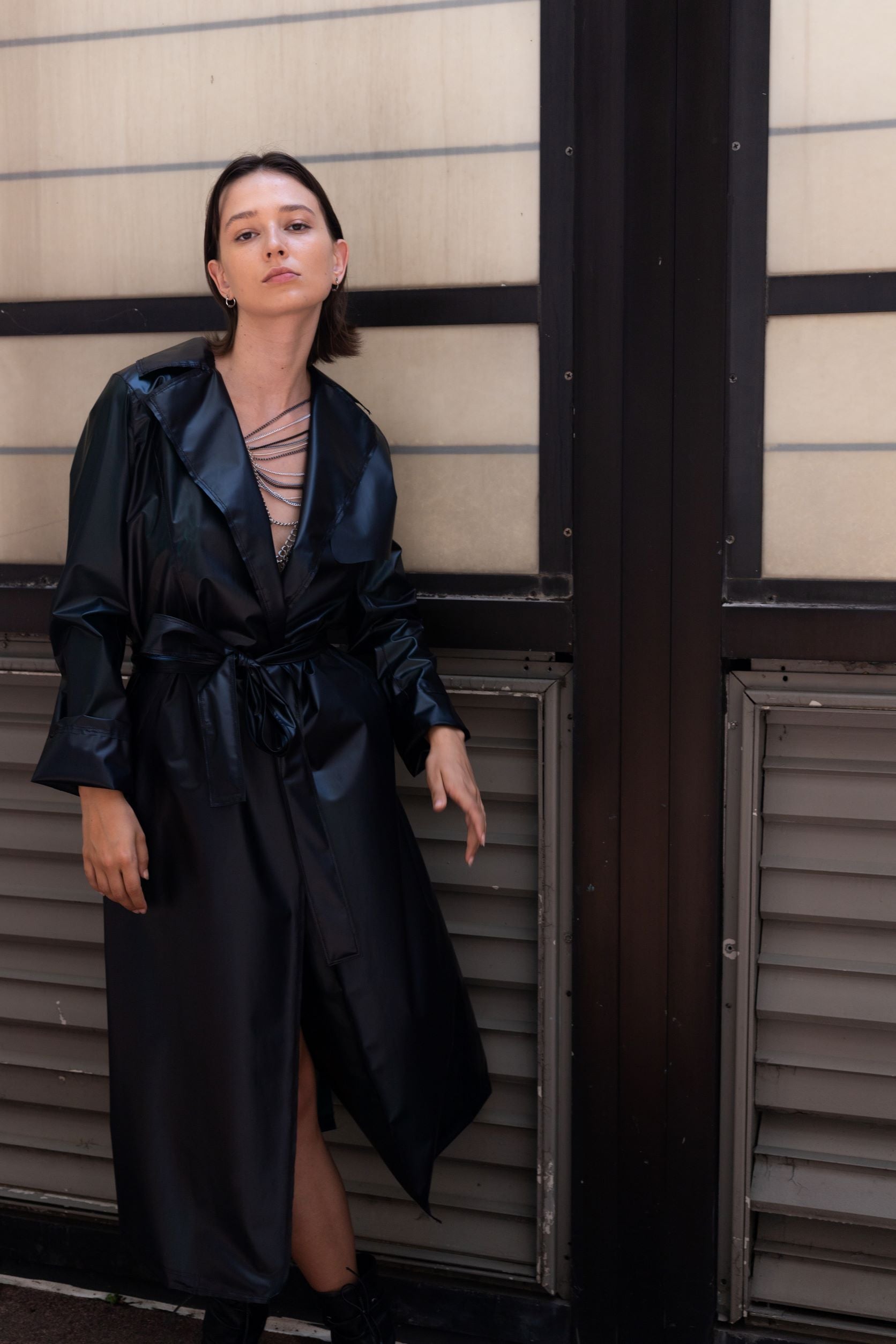 Woman wearing black transitional lambskin trench coat with belt and metal chain embroidery