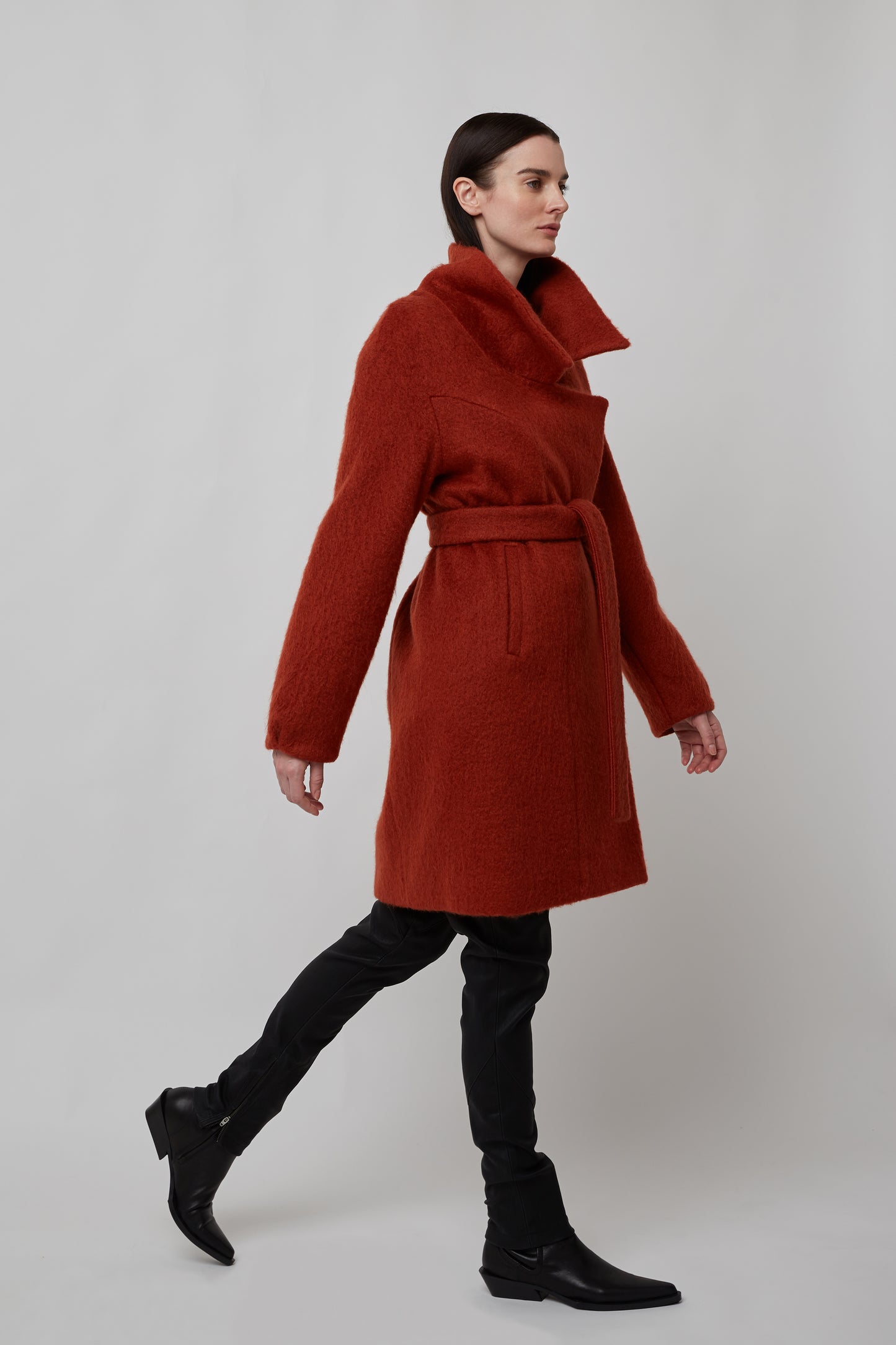 Woman wearing a mohair double breasted coat with wide collar cut in rust over black pants