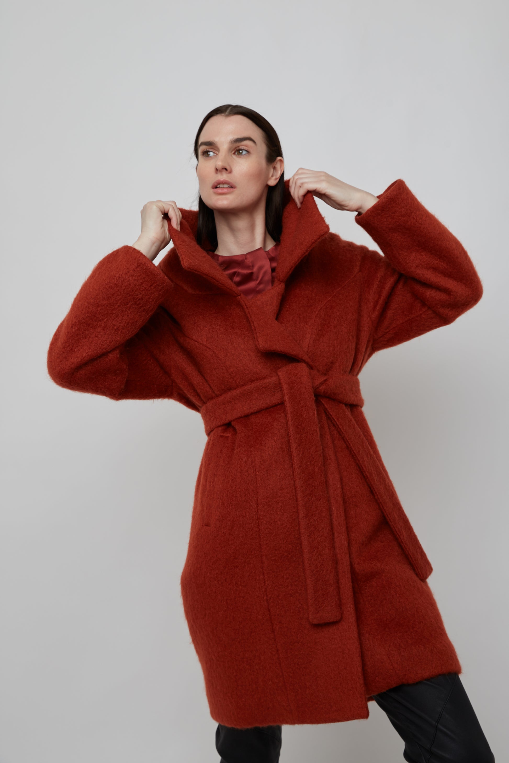 Woman in a rust colored mohair double breasted coat with wide collar cut and double self tie belt
