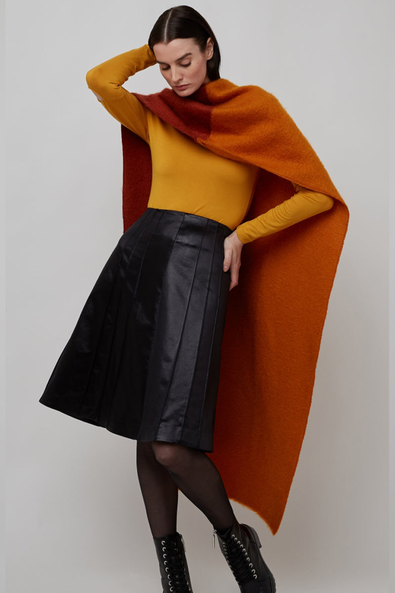 Woman wearing an orange scarf with yellow top and Spanish Lamp Skin Giselle leather skirt in Black