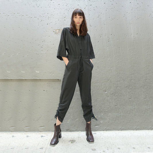 Woman posing while black striped linen, silk and viscose blend jumpsuit with drawstring waist, elbow length sleeves, and cropped length 